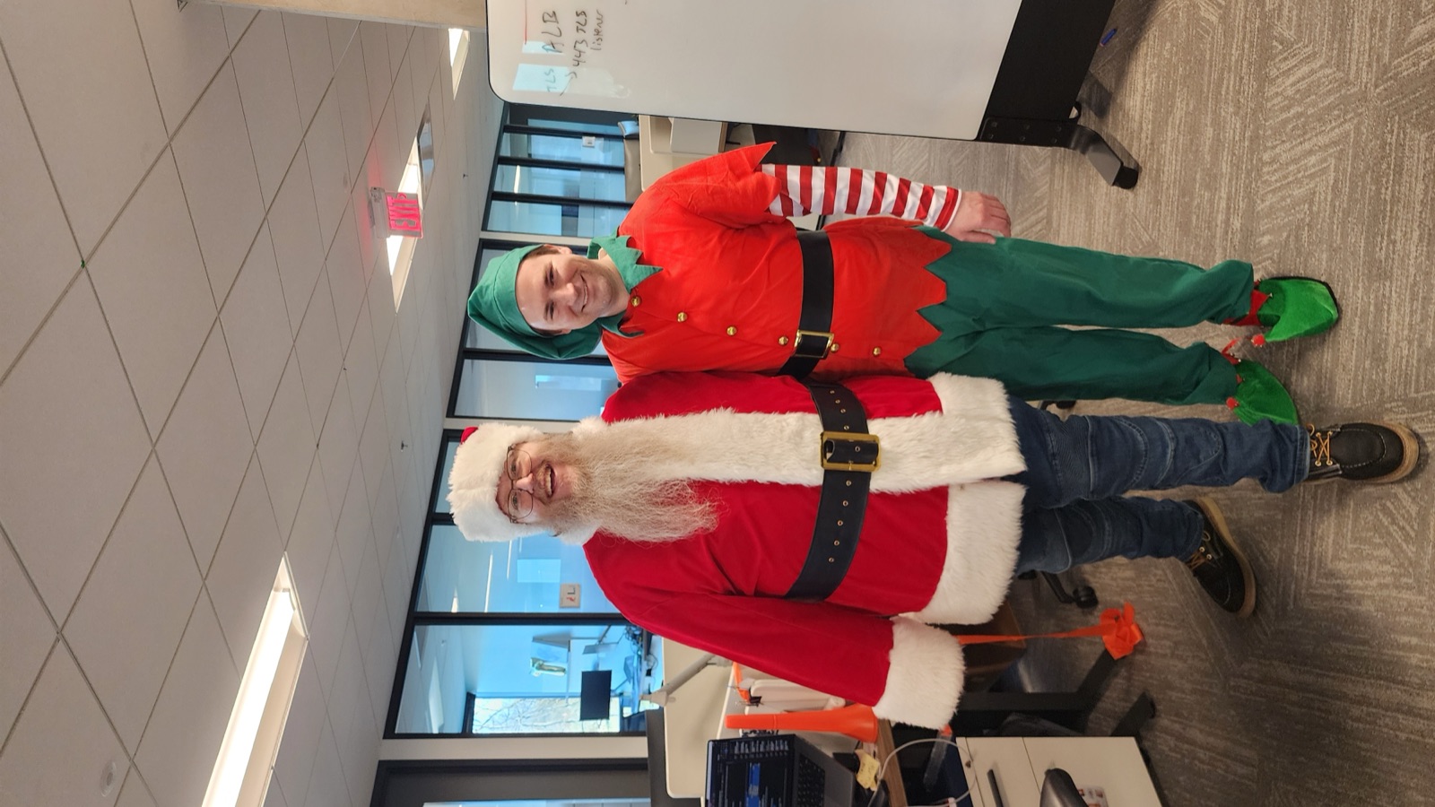 Santa with a cheerful elf at a workplace holiday event