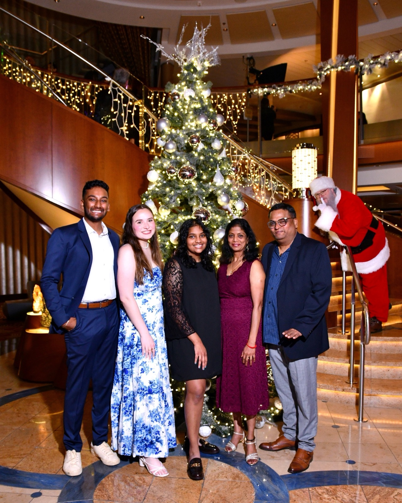 Santa photobombing a family photo by a Christmas tree